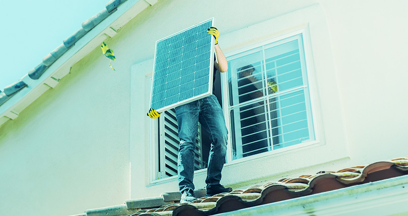 homme qui installe un panneau solaire sur le toit d'une maison